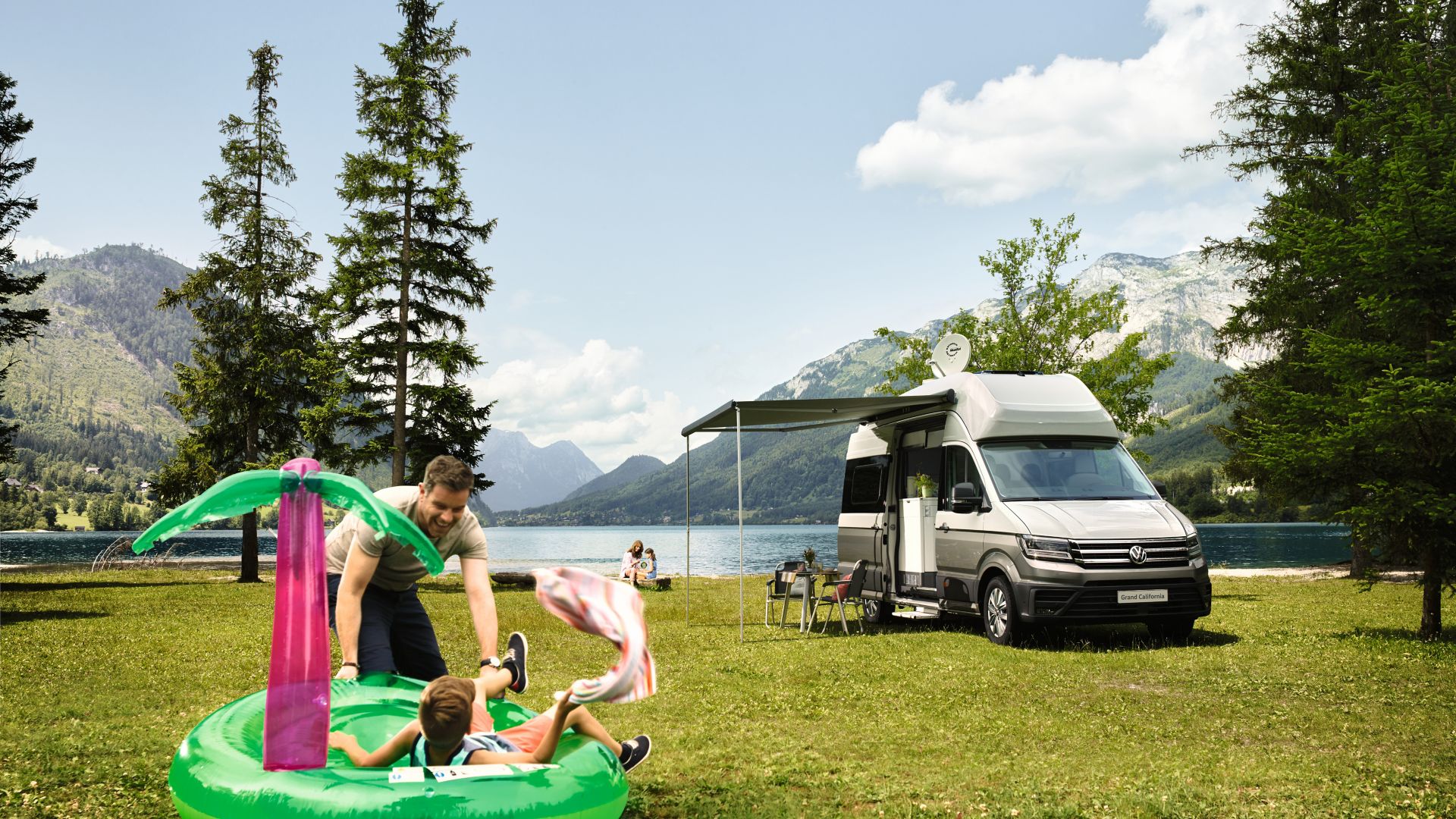 VW Grand California vue de face devant un lac avec famille