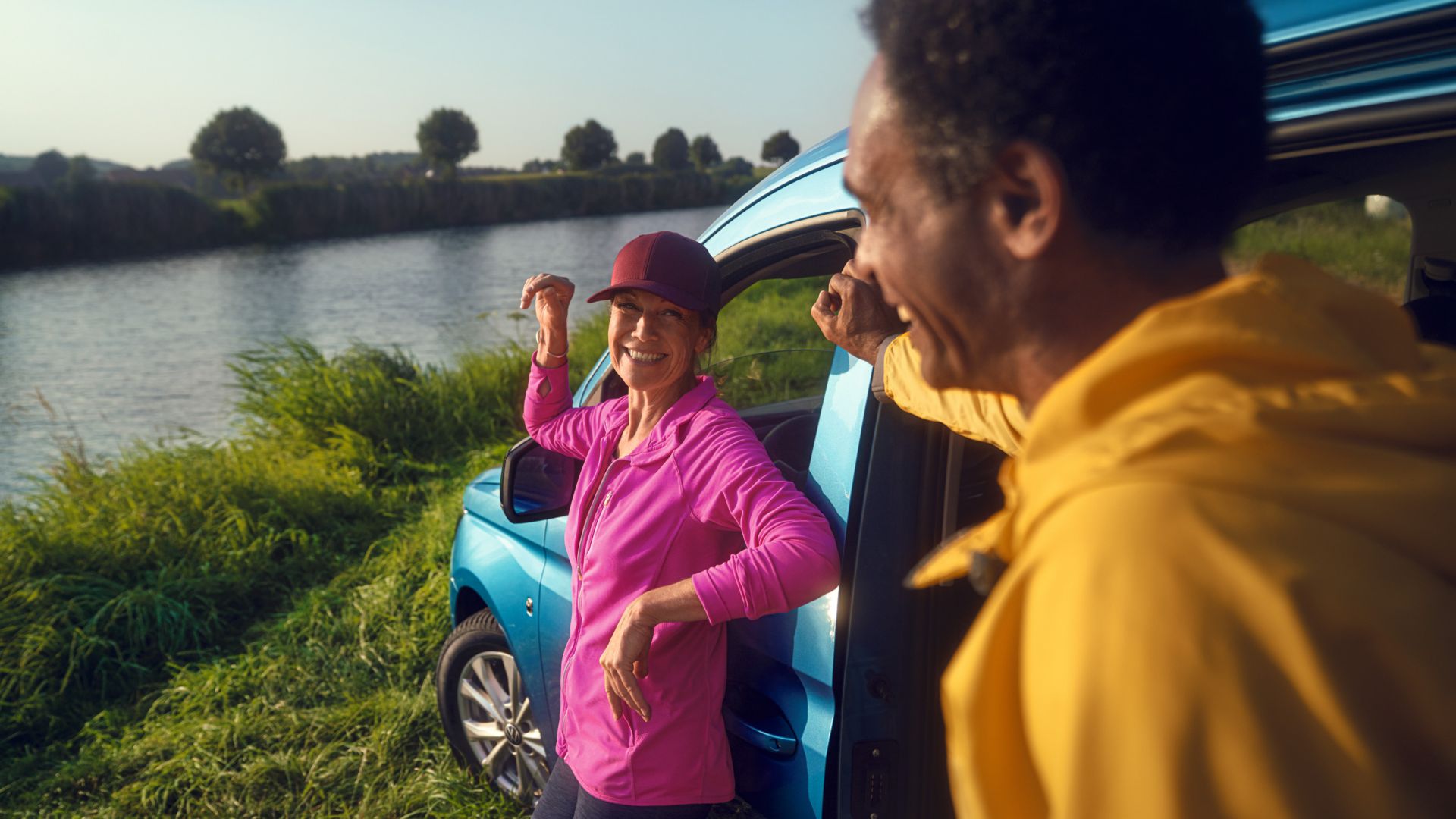 Blauer Caddy California mit Frau und Mann am See