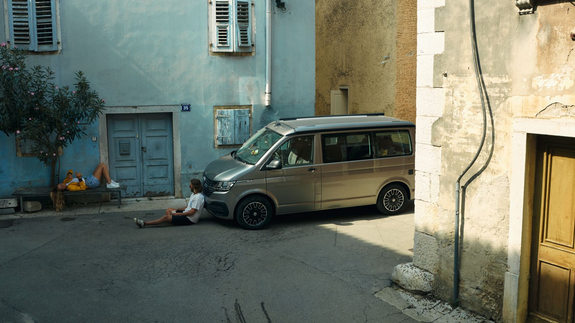 Silberner VW California Beach Seitenansicht in mediterraner Strasse