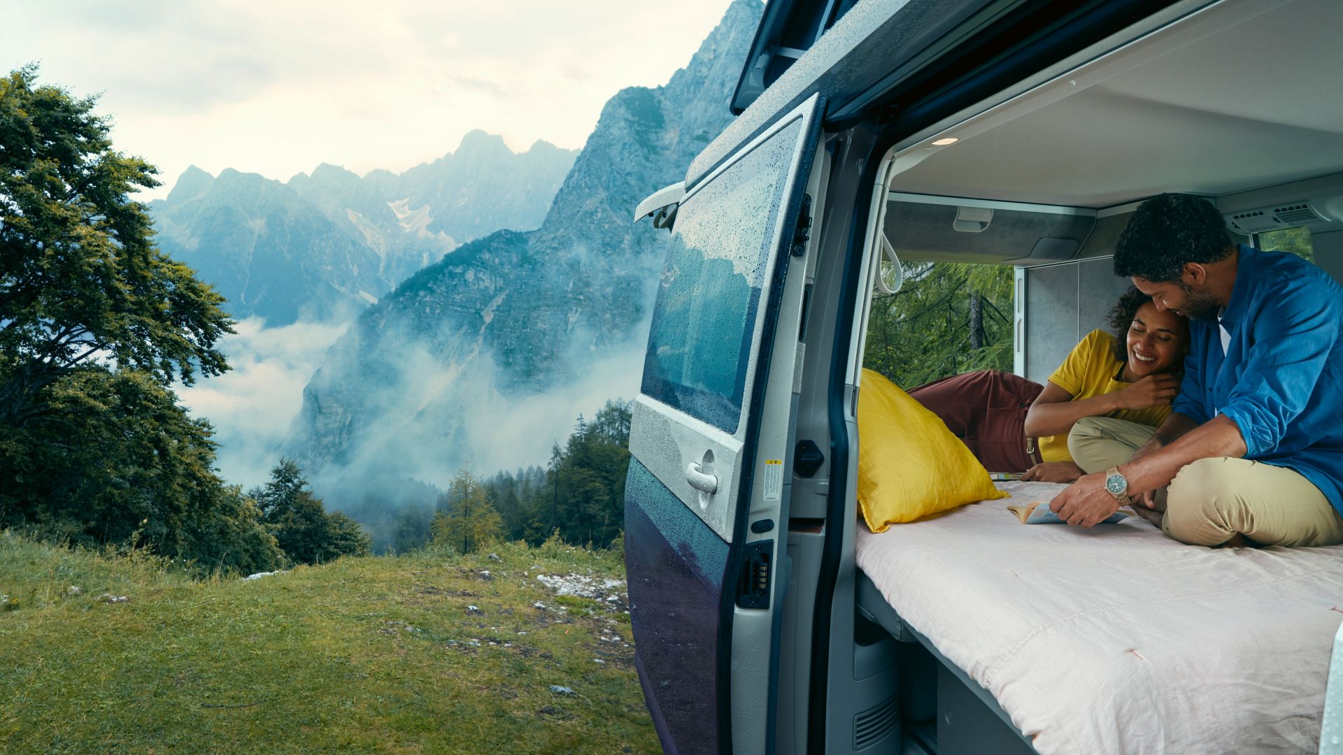 Side of the VW California Ocean with open door and couple inside in the mountains
