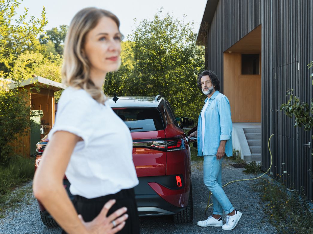 Frau und Mann stehen bei E-fahrzeug das geladen wird