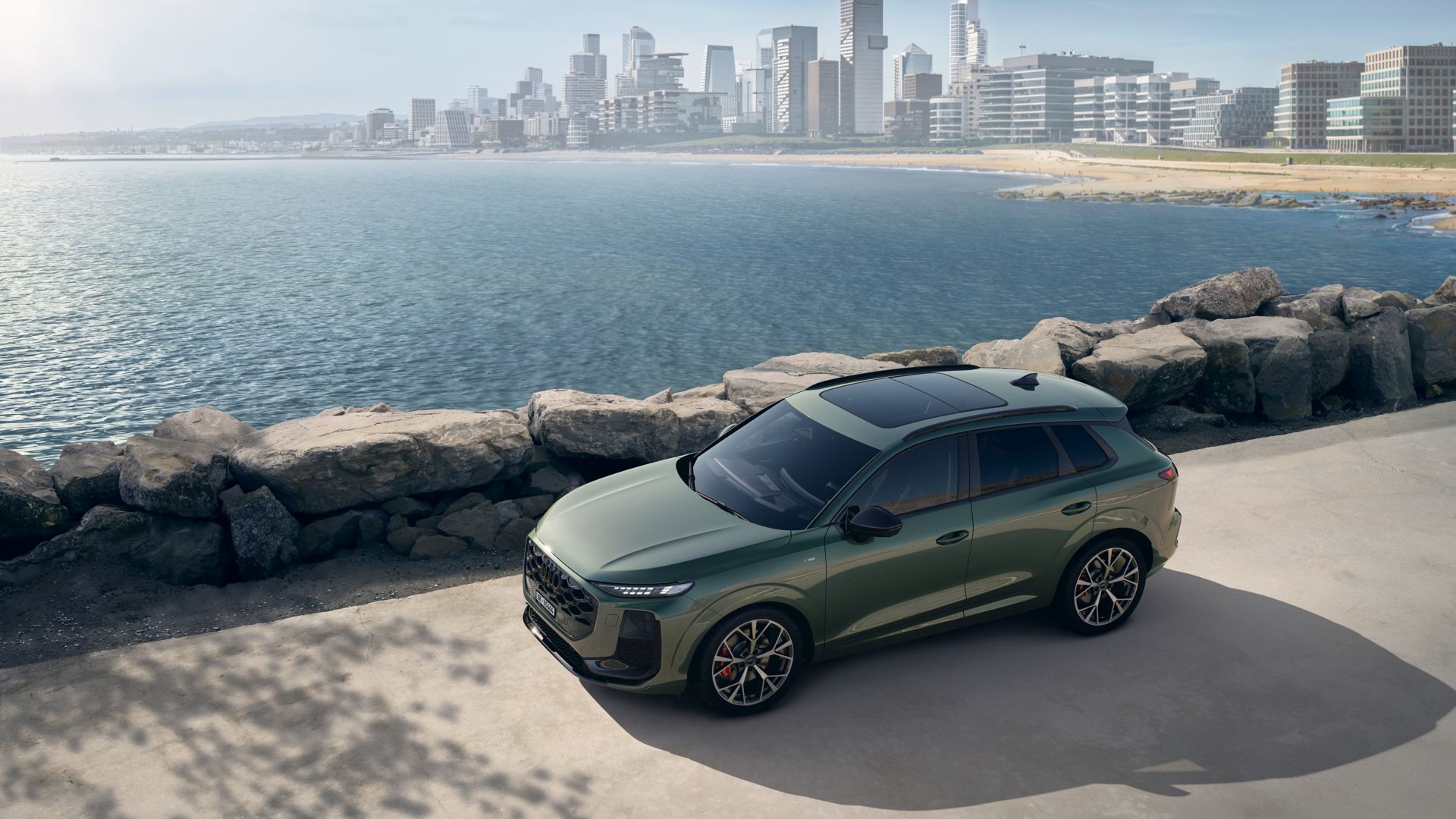 Audi Q3 vue de face et latérale avec une ville à la mer derrière