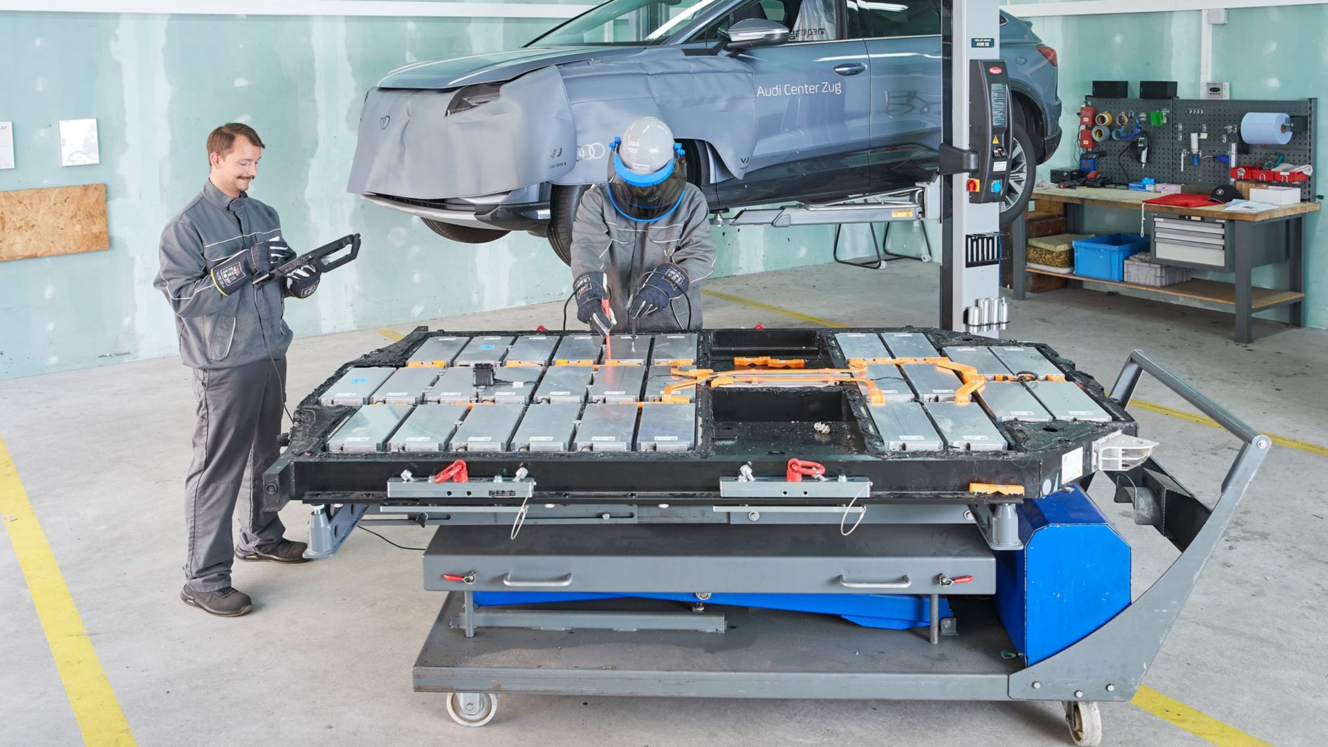 Werkstattchef Stefan Emmenegger arbeitet an einem Elektroauto im Hintergrund ein Audi