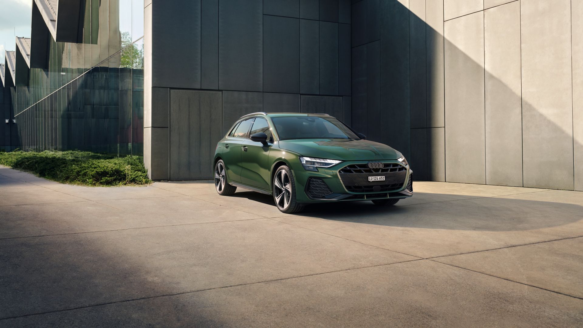 Green Audi A3 Sportback parked in front of a building front and side view