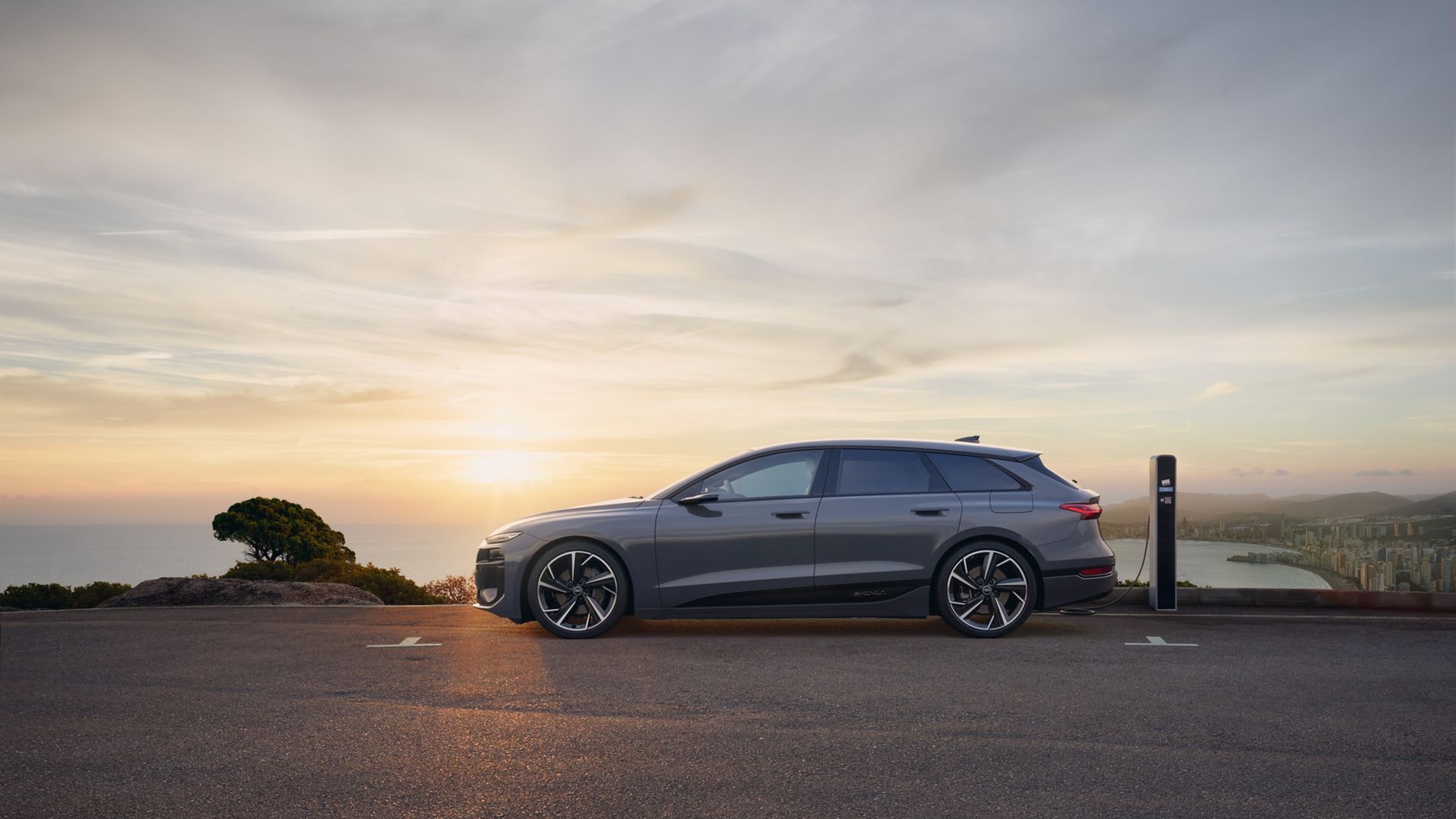 Grey Audi A6 e-tron side view, next to a building