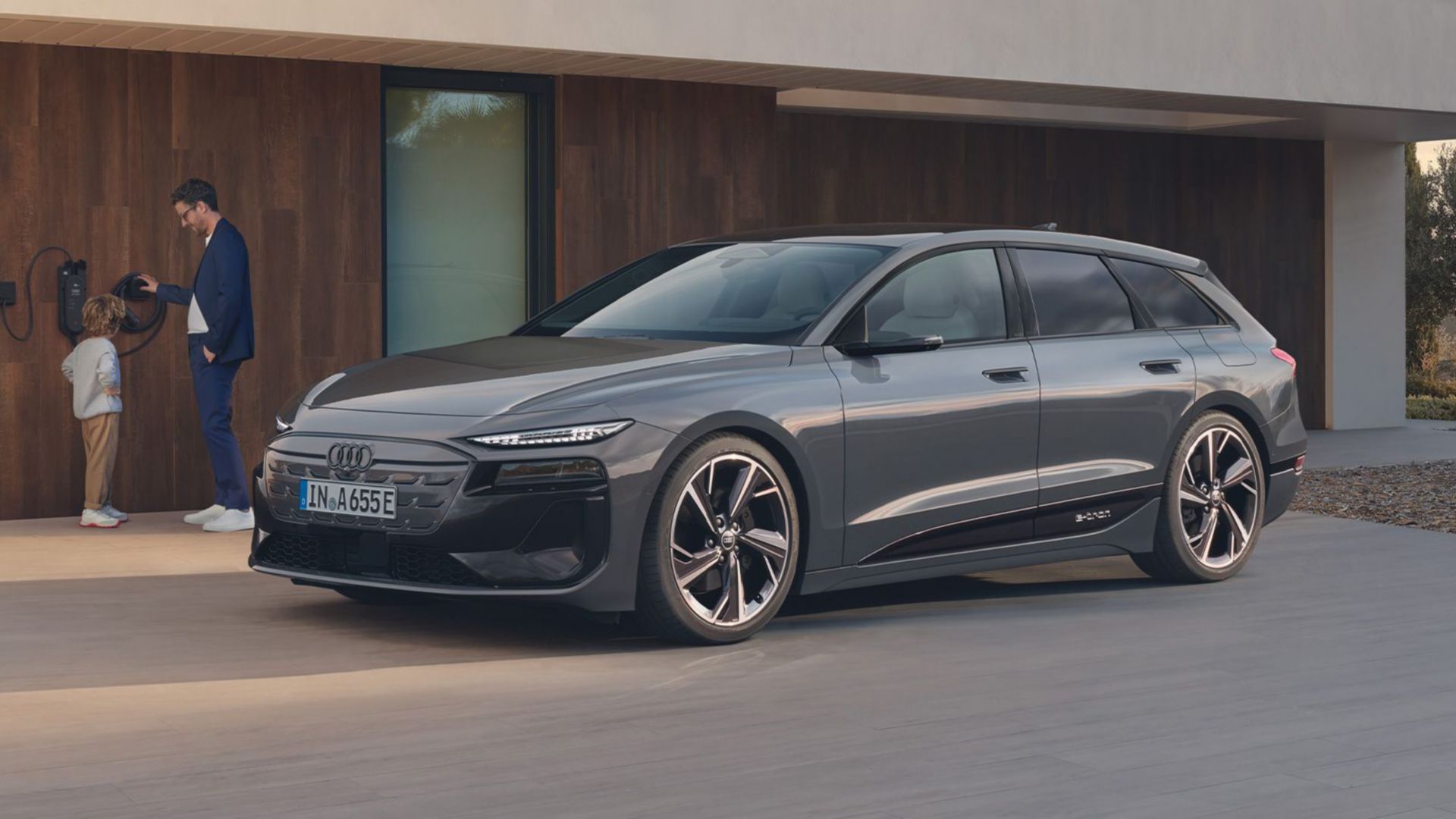 Côté de l’Audi A6 e-tron gris devant une maison