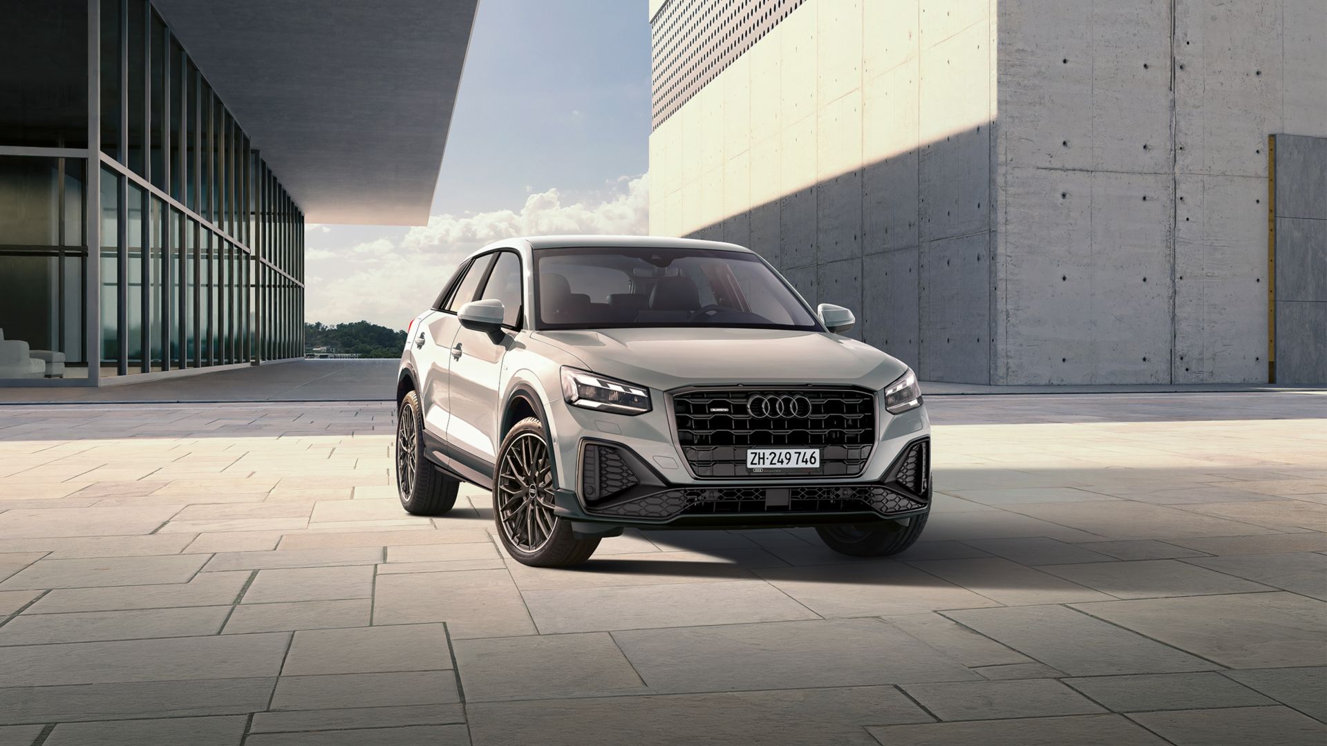 Audi Q2 grise vue de face à côté deux maisons