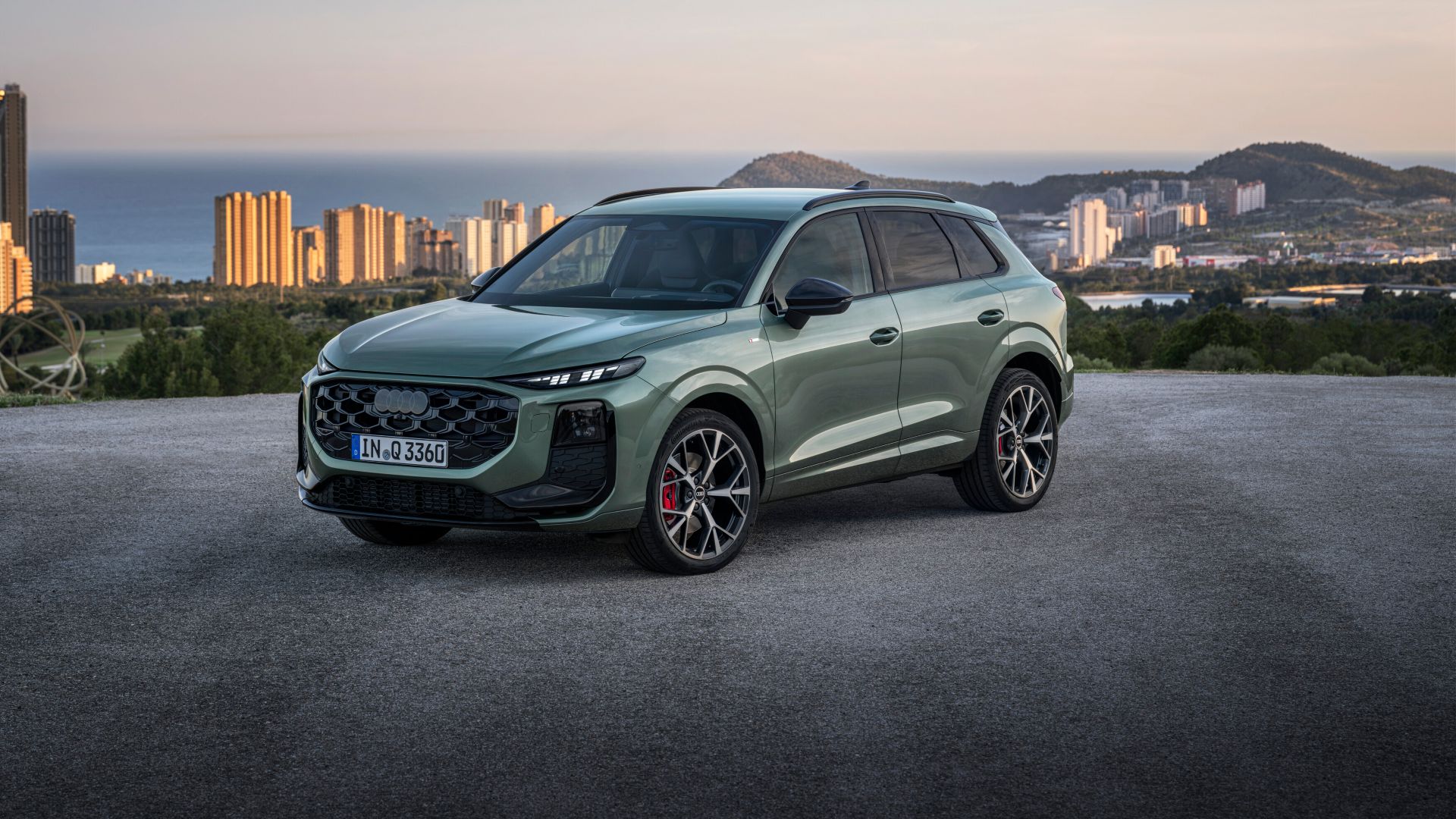 Audi Q3 vue de face et latérale avec une ville à la mer derrière