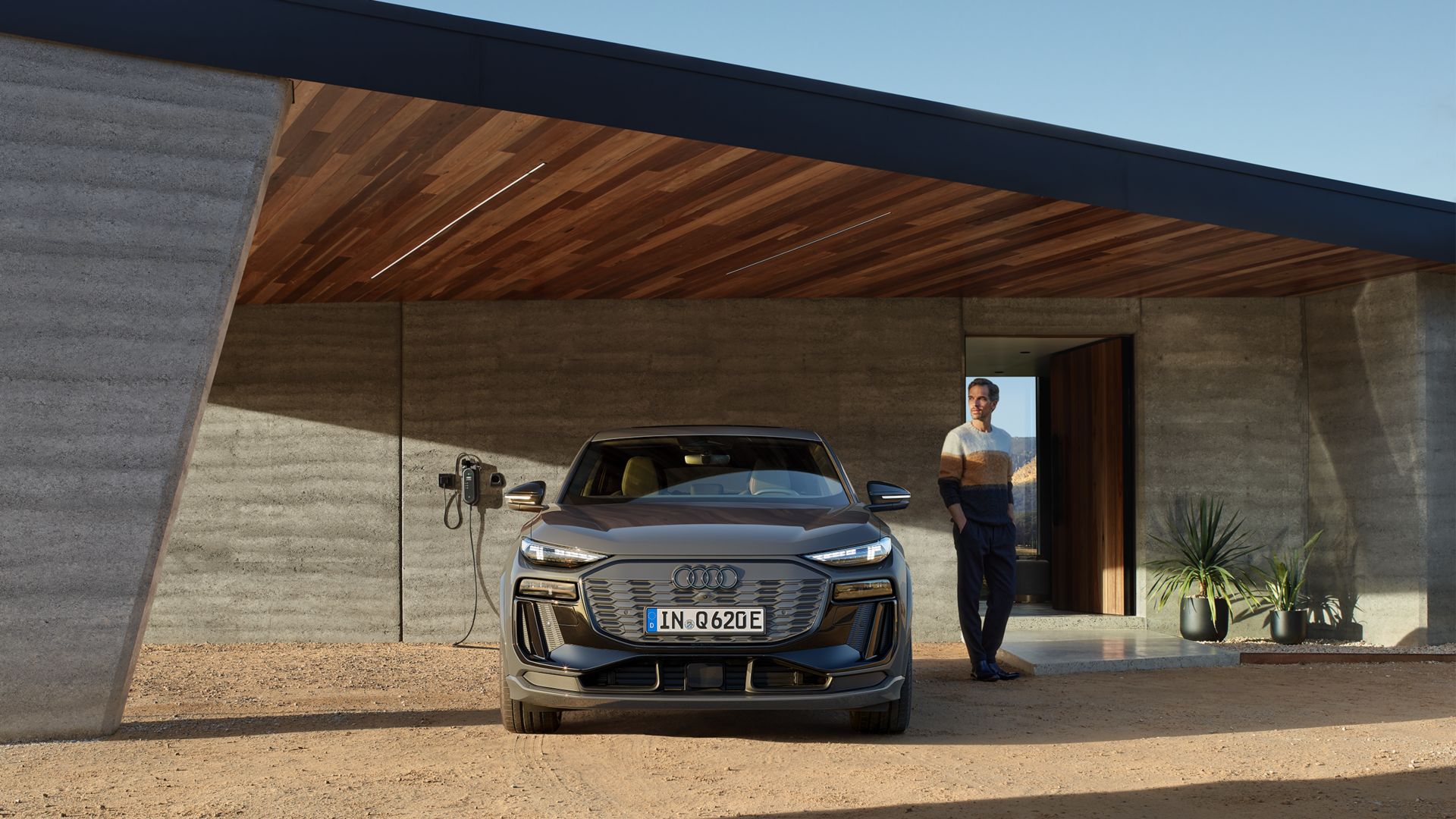 Audi Q6 e-tron nero, vista anteriore davanti a una casa, con un uomo accanto