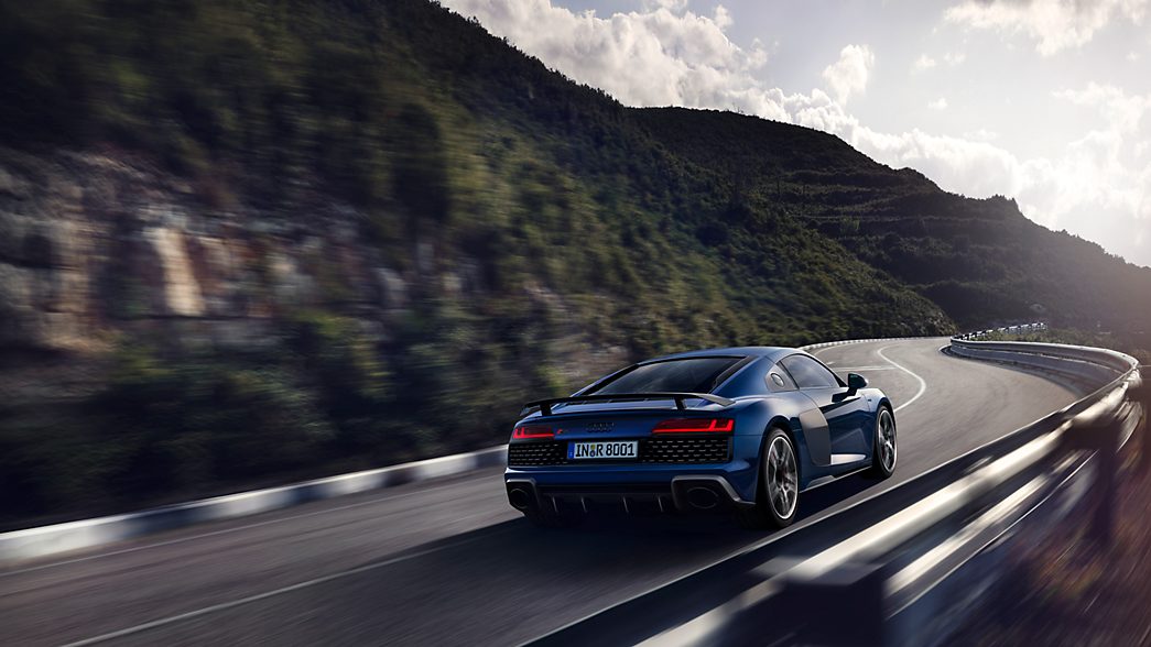 Audi R8 Coup&eacute; in blue on a country road, viewed from the rear 