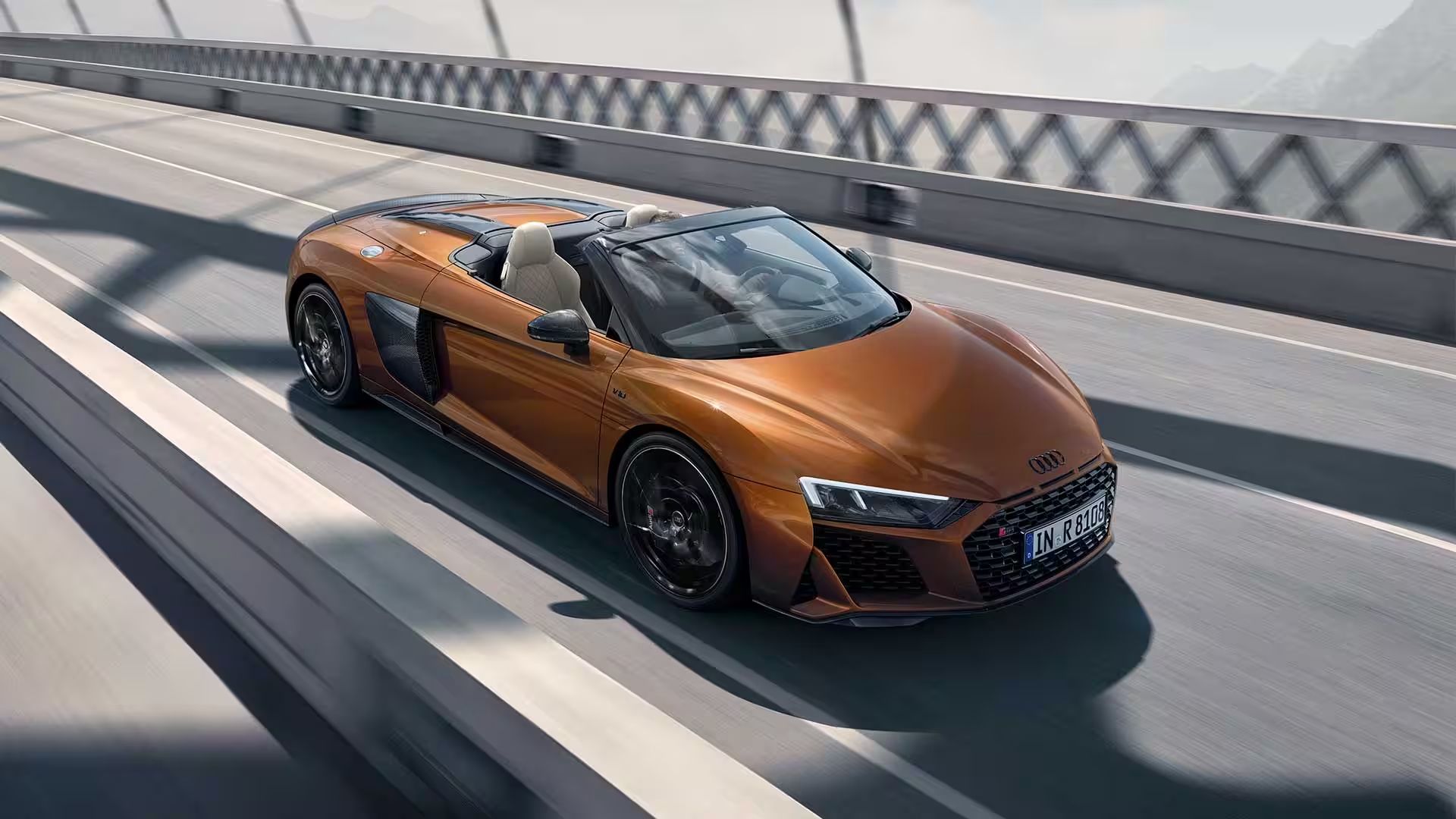 Audi R8 Spyder arancione sul ponte dell'autostrada