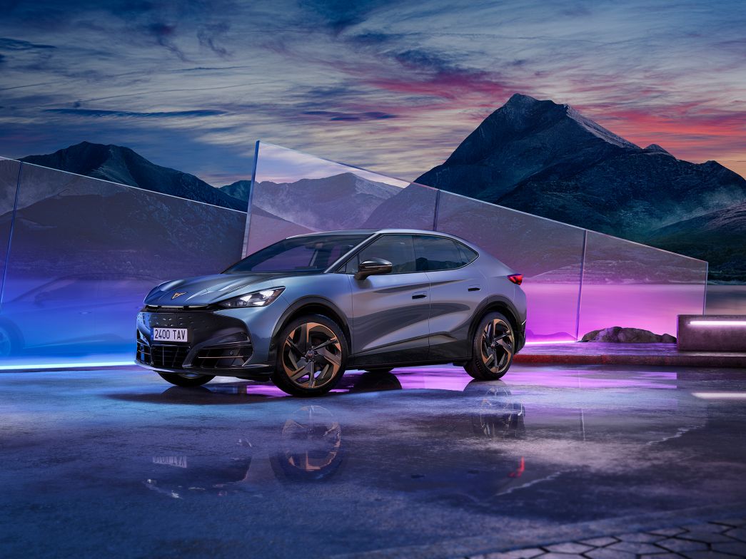 Violetter CUPRA Tavascan Seitenansicht mit Bergen im Hintergrund