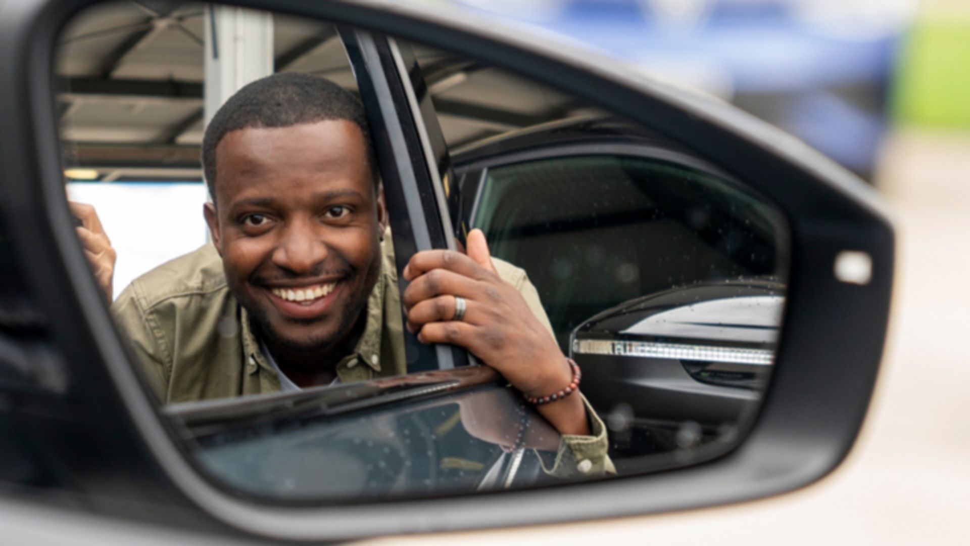 Comedian Charles Nguela schaut in Autospiegel