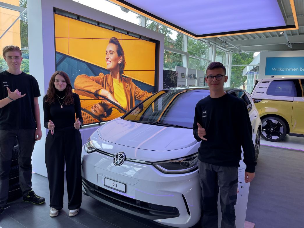 3 neue Lernende vor einem Fahrzeug