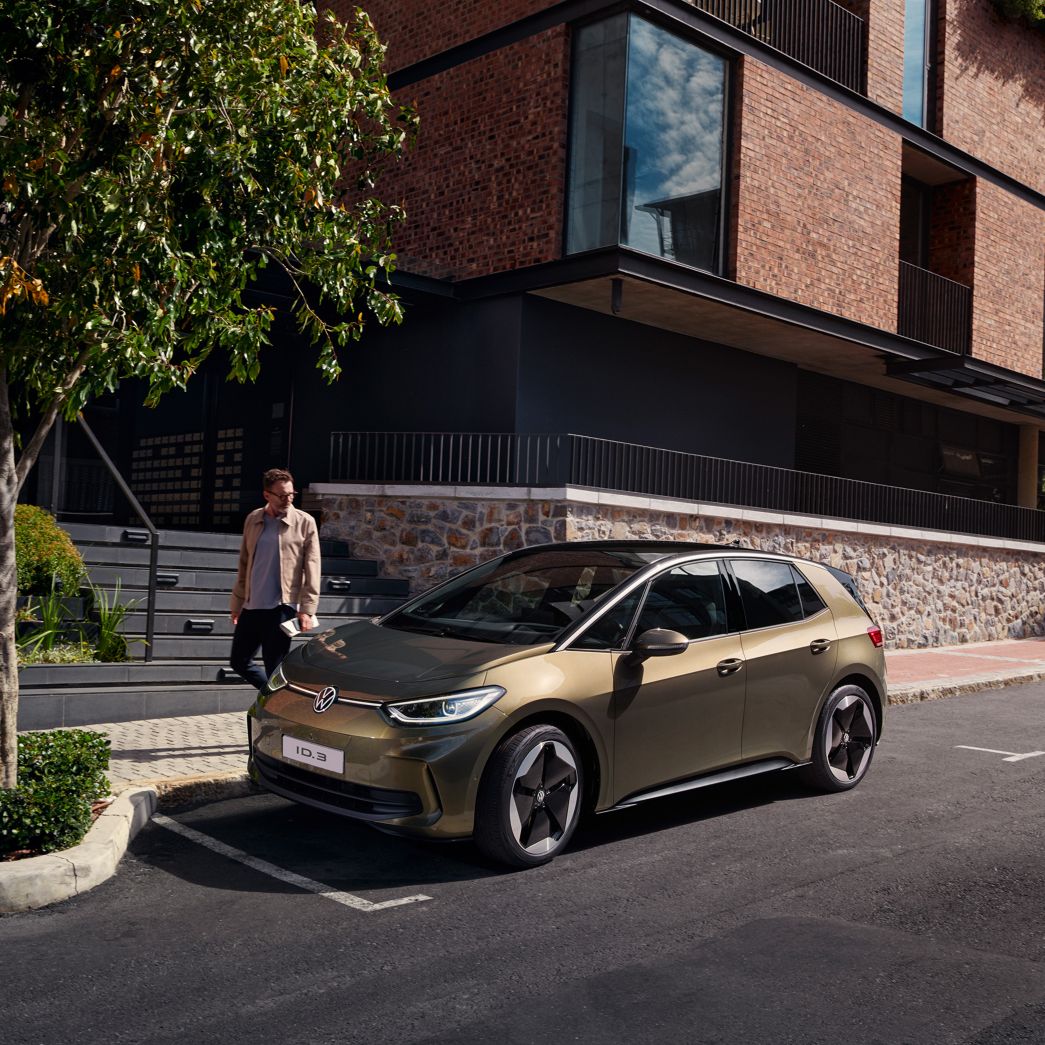 Olivgrüner VW ID.3 auf Parkplatz mit Mann daneben