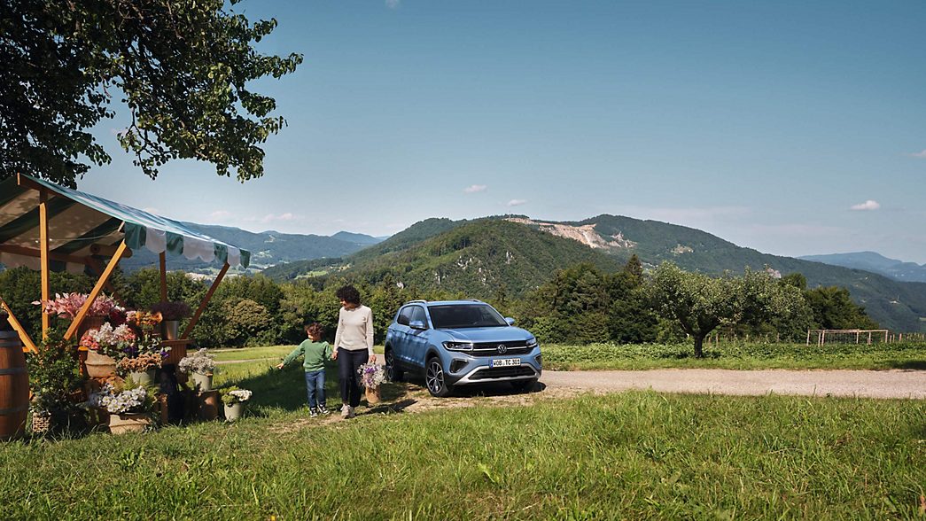 VW T-Cross blu in natura con montagne