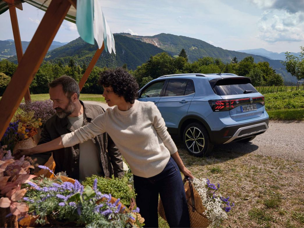 Frau an Marktstand, im Hintergrund der neue VW T-Roc