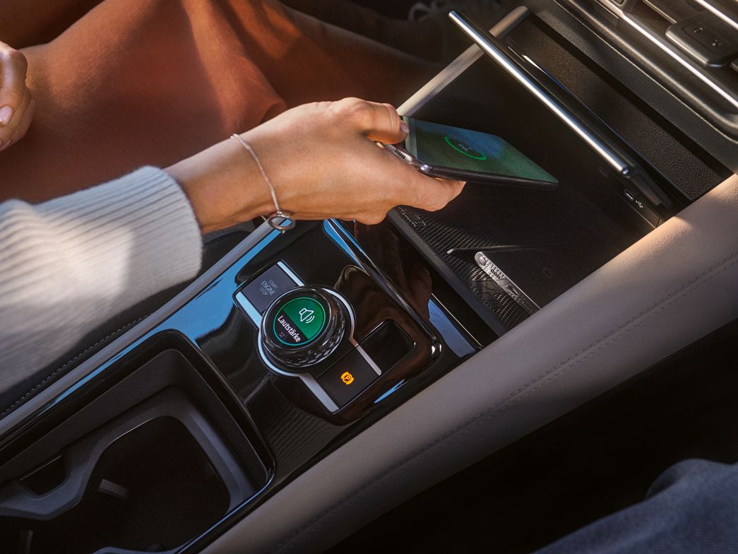 Frau legt Smartphone in Ladeschale des VW Tiguan