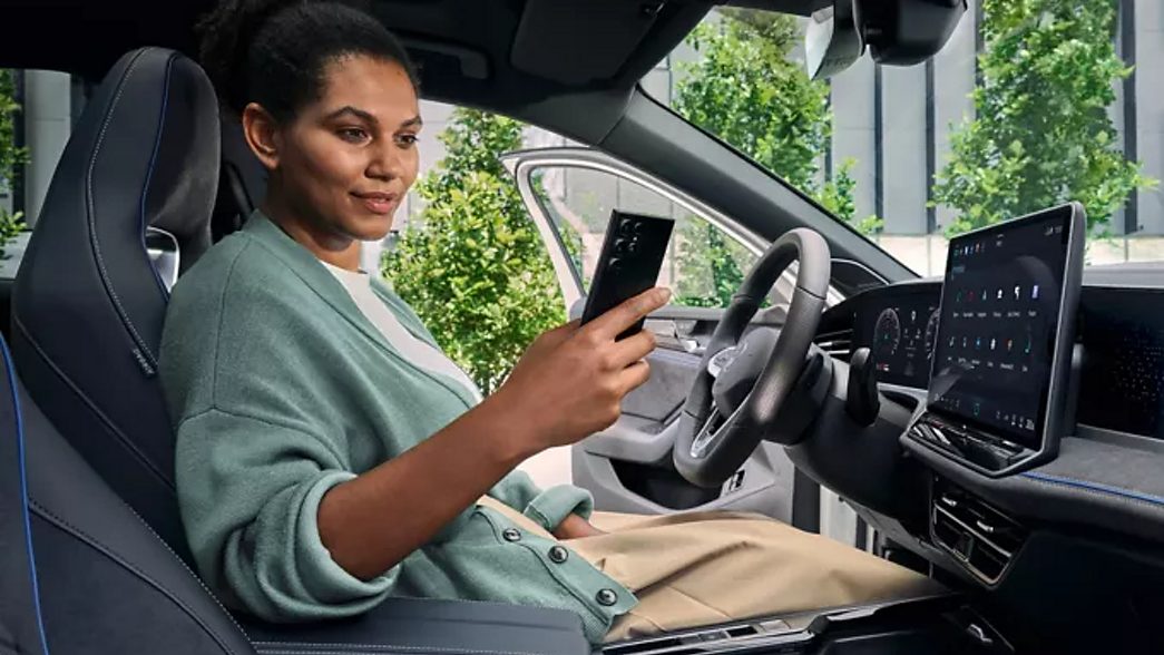 Une femme avec un smartphone dans l'habitacle de la nouvelle VW Passat 