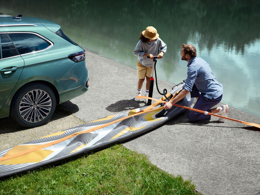 Father and child with canoe next to the new VW Passat 