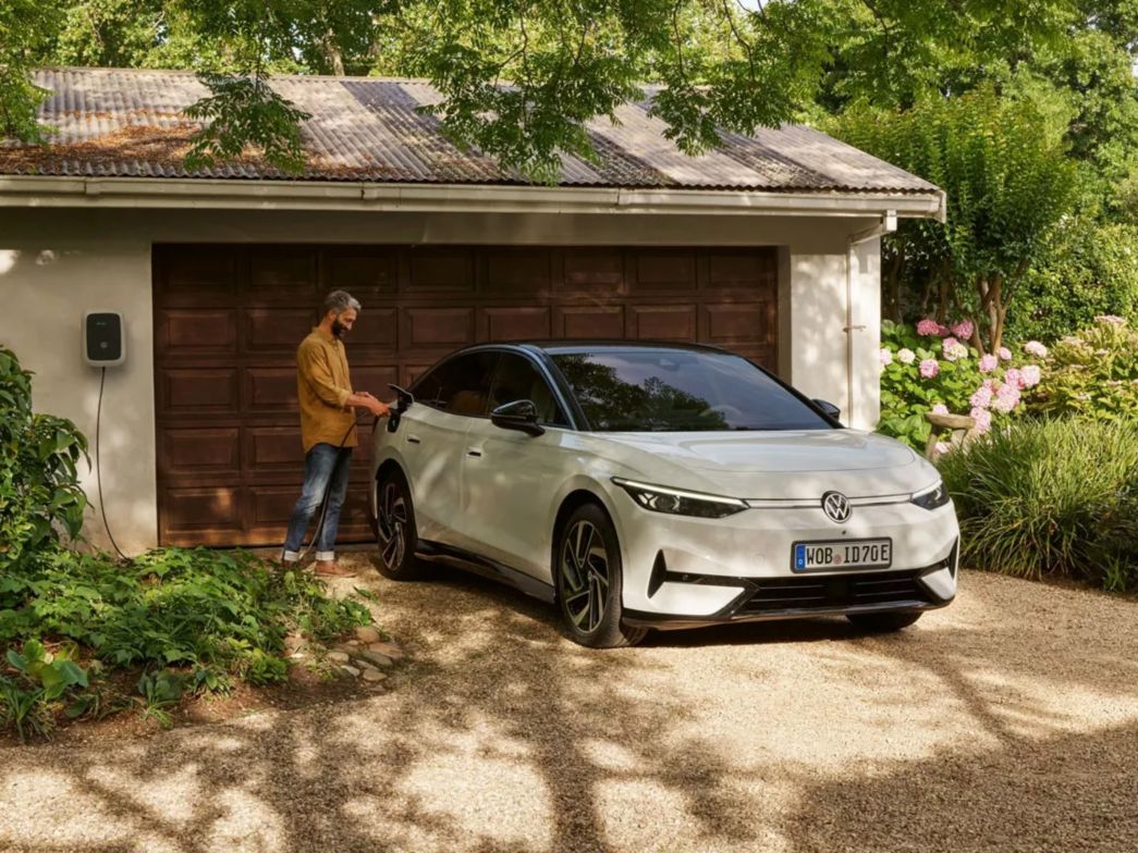 Un uomo collega la VW ID.7 alla stazione di ricarica domestica 