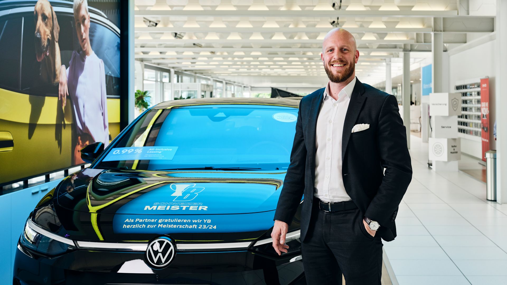 Adrian Ringgenberg, AMAG Verkaufsberater neben einem schwarzen VW ID.7