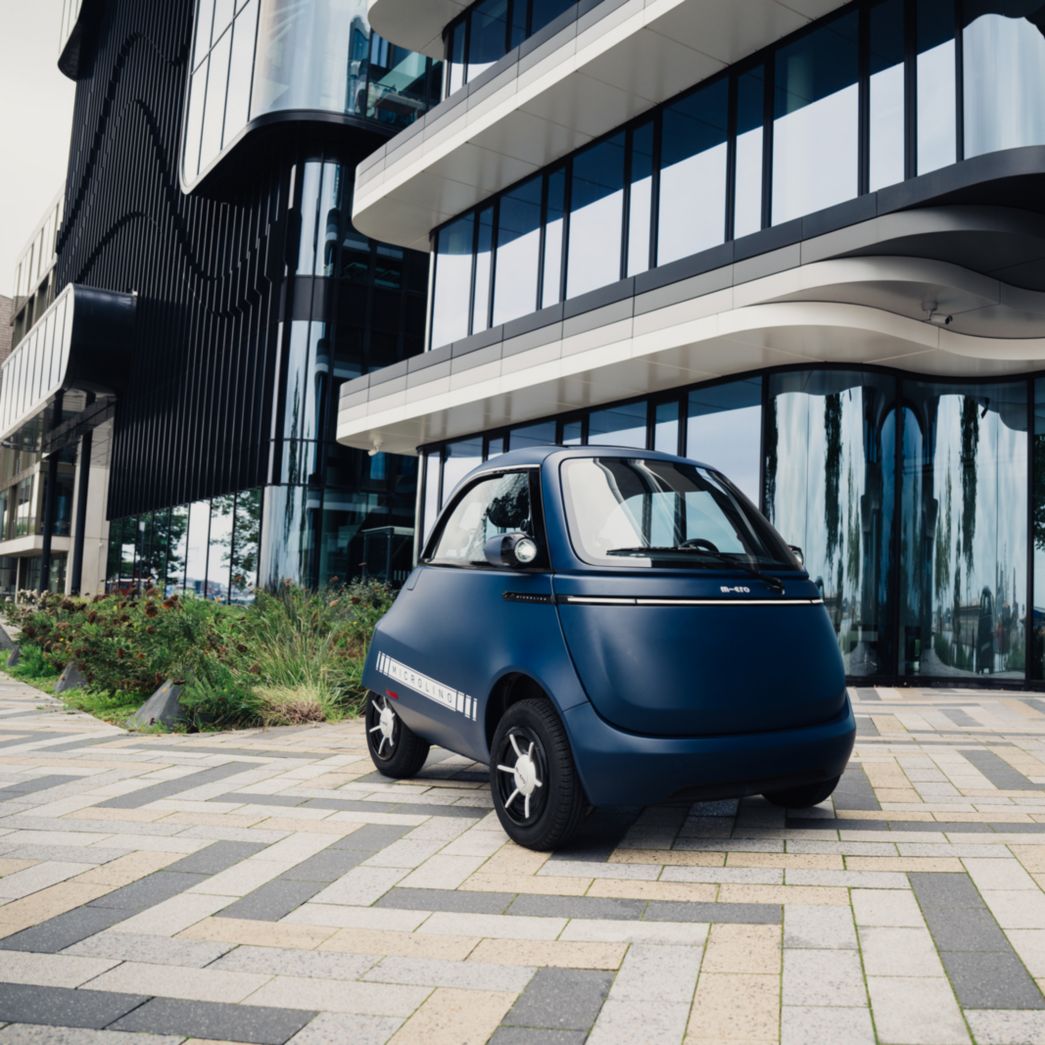 Microlino blue in front of a building