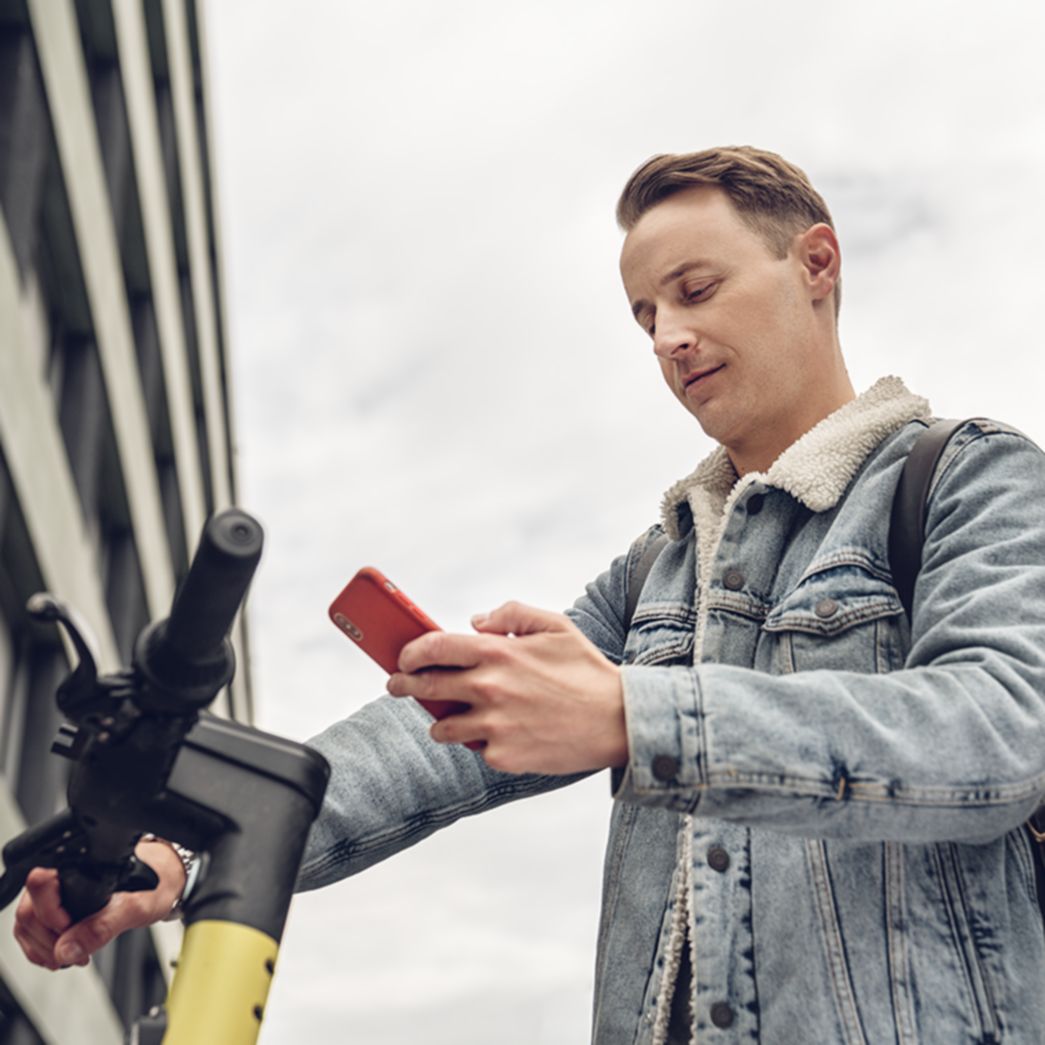 Mann auf E-Scooter am Handy