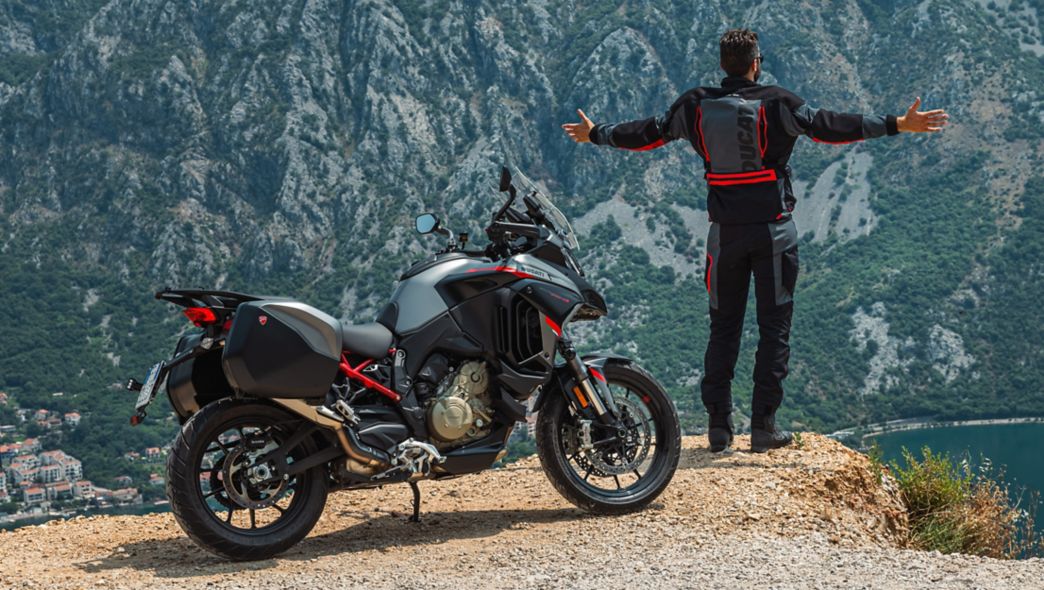 Man standing next to a motorcycle by some rocks