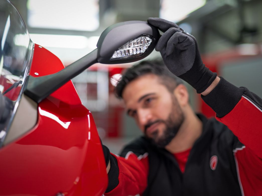 Mechaniker schaut Motorrad Spiegel an