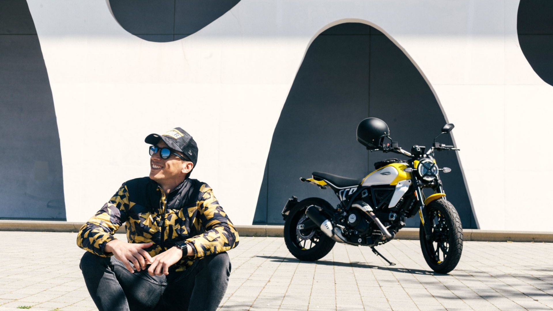 Man sitting in the foreground, his Ducati parked in the background