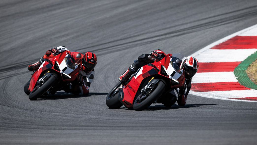 Zwei Ducati Fahrer/innen auf der Rennstecke in einer Kurve